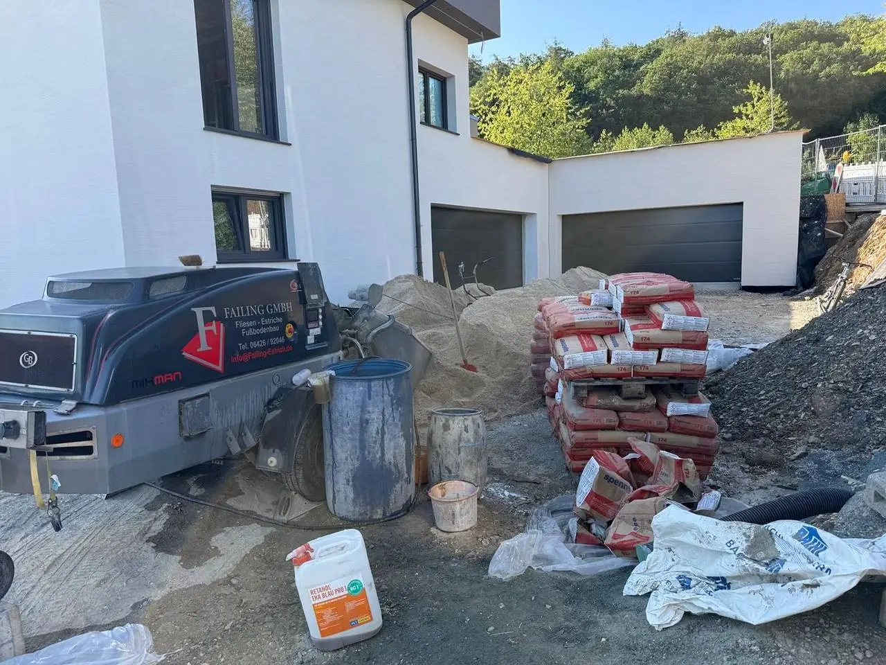 Estrichpumpe und Zementpaletten vor einem Wohnhaus